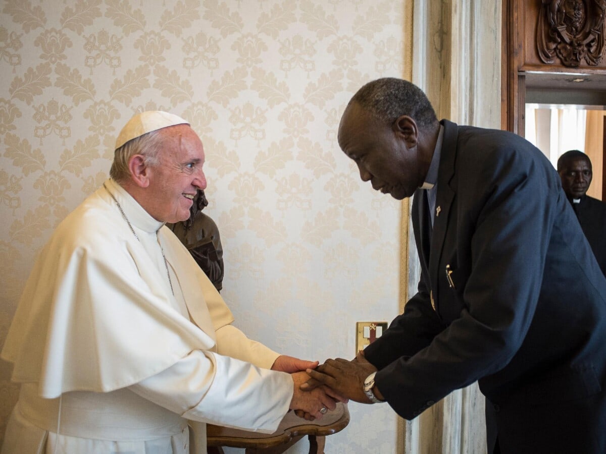 Pope Francis warmly greets Peter Gai, president of the Presbyterian Church of South Sudan, shaking hands.