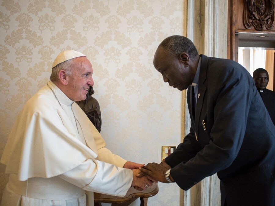 Pope Francis warmly greets Peter Gai, president of the Presbyterian Church of South Sudan, shaking hands.