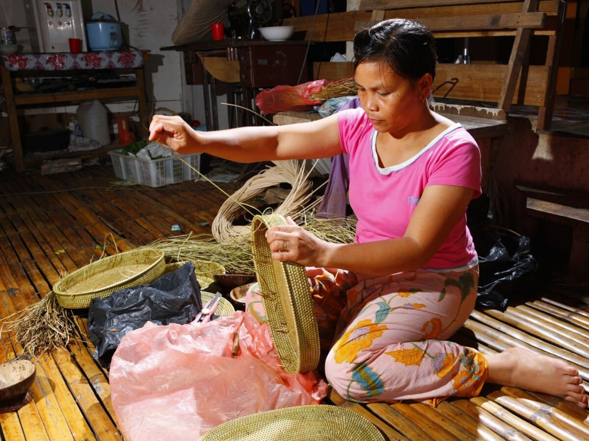 una mujer joven haciendo una cesta de rinago en una casa larga rungus. 2011, sabah