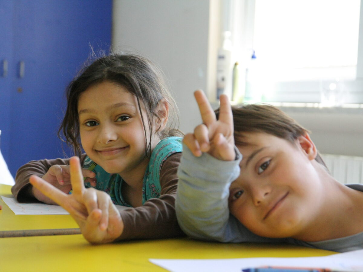 Dos niños del proyecto hacen el signo de la paz.